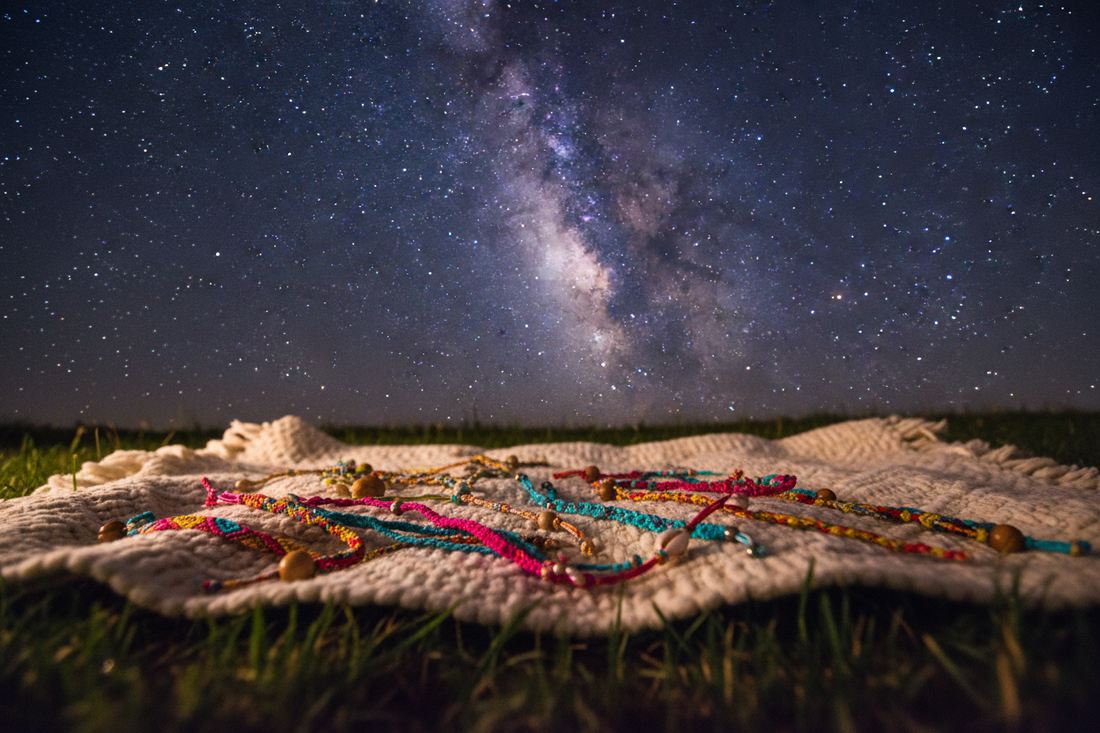 A blanket with friendship bracelets under a starry night sky