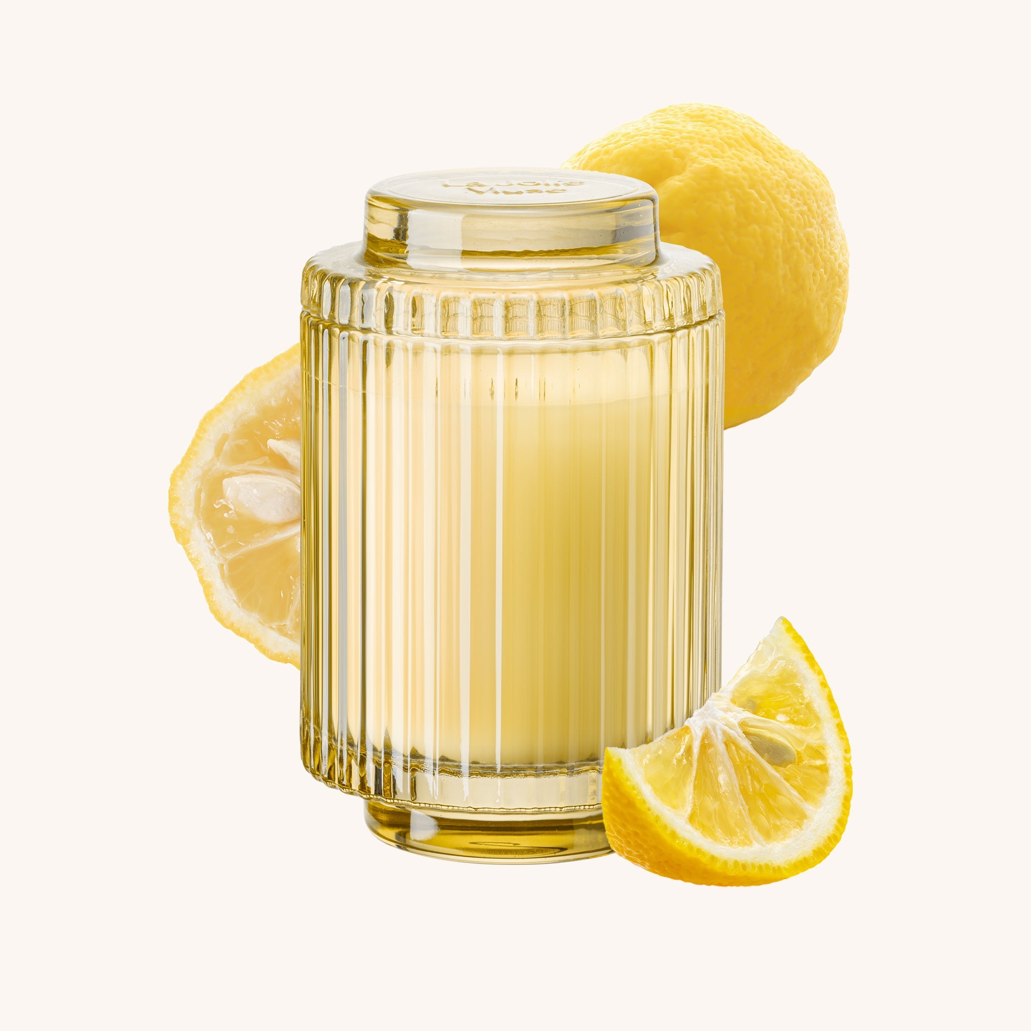 Clear glass container with ribbed design surrounded by lemons on a white background