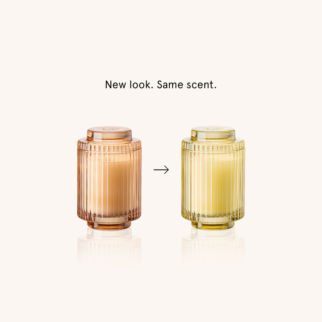 Two glass candle holders with different colors on a white background, labeled 'New look. Same scent.'
