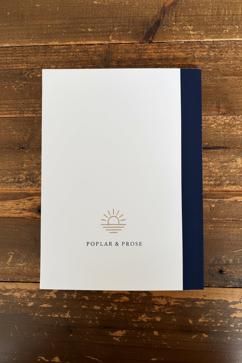 White notebook with blue binding on a wooden surface, featuring 'Poplar & Prose' branding.