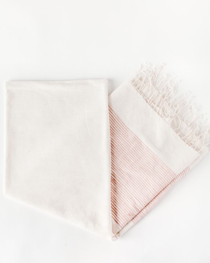 folded towel in blush with tassels on a white background.