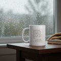 White mug with original quote on a wooden table in front of a rainy window, in 11 oz