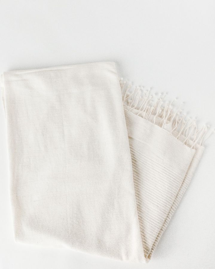 Natural Shore Towel folded with fringe on a white background, showing hand-spun cotton texture