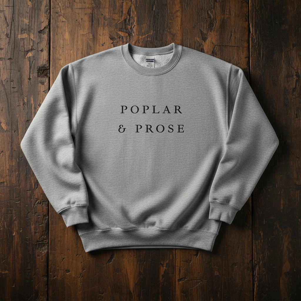 Gray sweatshirt with 'Poplar & Prose' text on a wooden surface