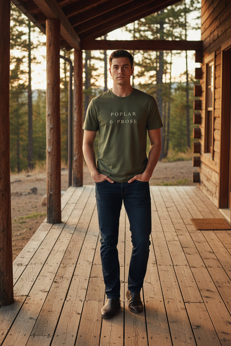 Green Poplar & Prose Organic Tee on Man standing on a cabin's porch