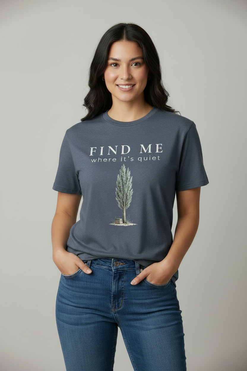 Woman wearing a blue t-shirt with a tree graphic and 'Find Me Where It's Quiet' on a plain background
