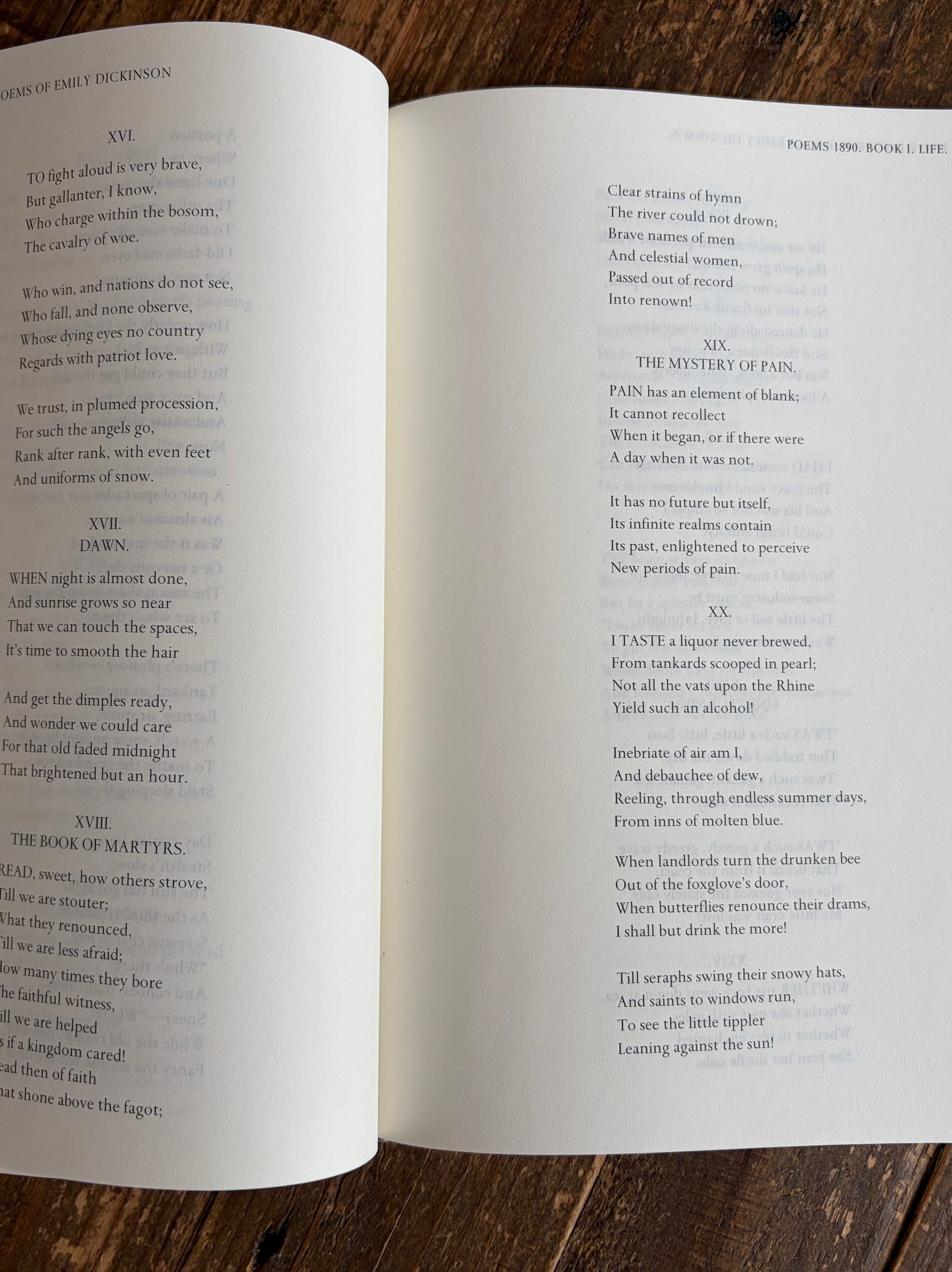 An open book showing printed text pages, photographed from above on a dark wood surface.