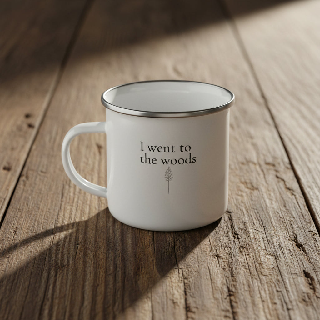 White enamel mug with "I went to the woods" and a small tree design on a reclaimed wood surface