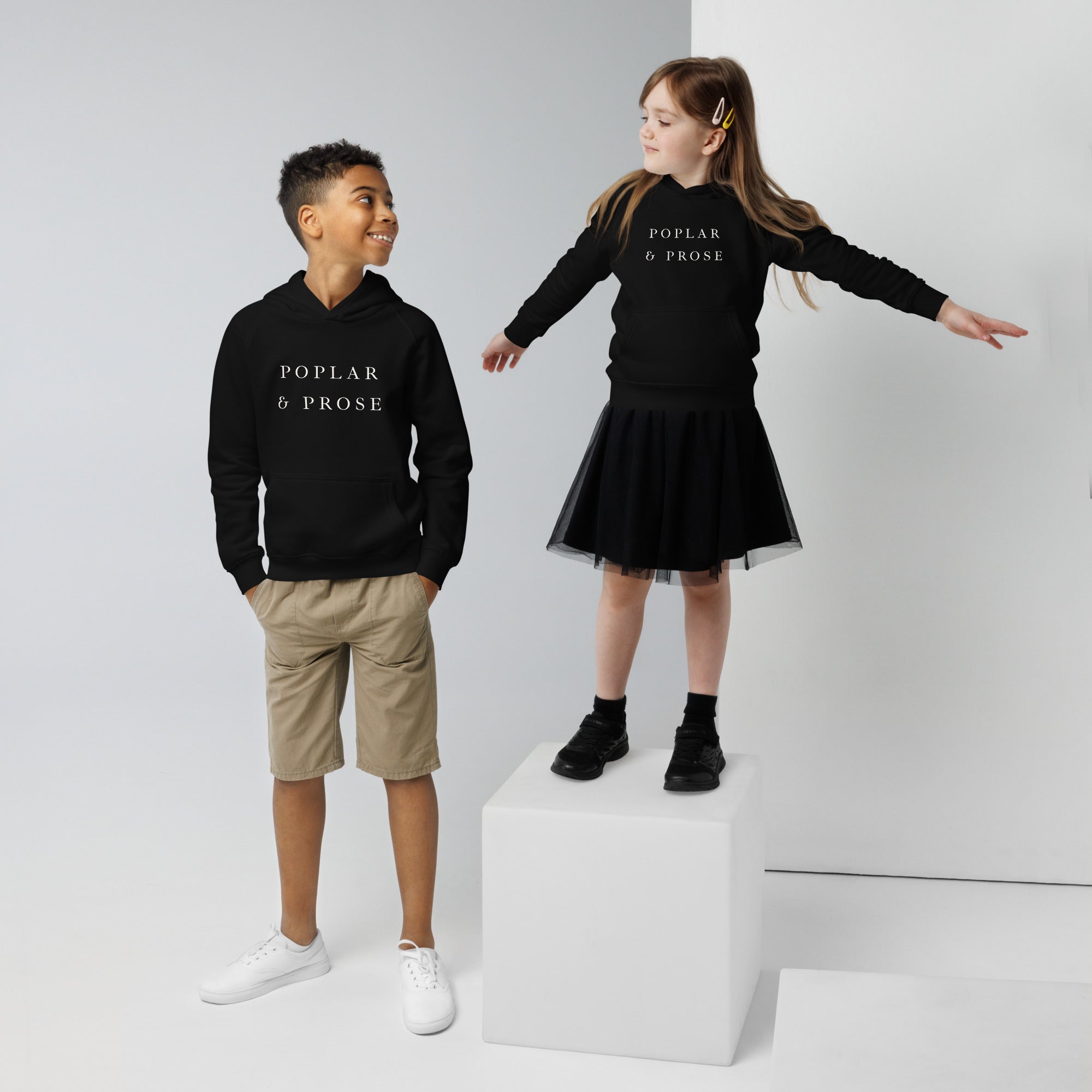 Two children wearing black hoodies with atom symbol designs on a white background