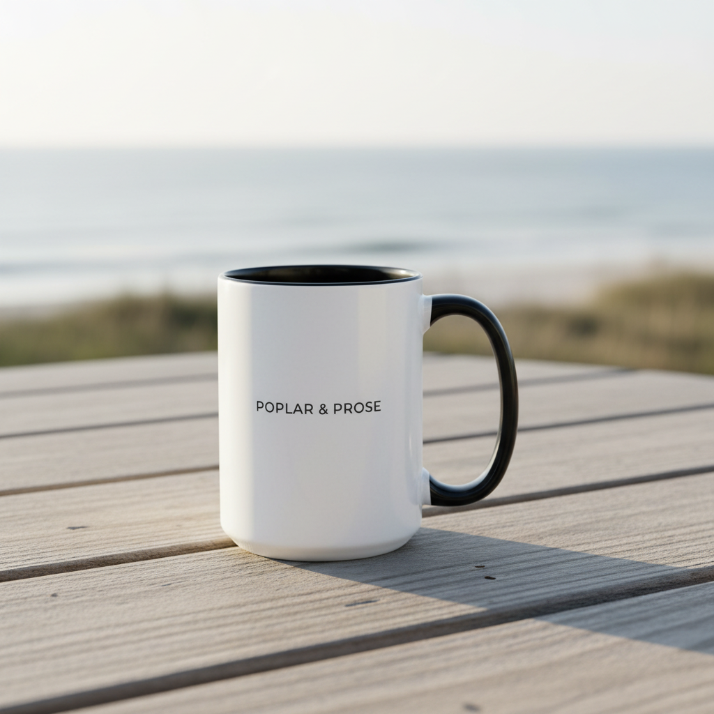 White mug with black handle and text 'Poplar & Prose' on a wooden surface with a beach background