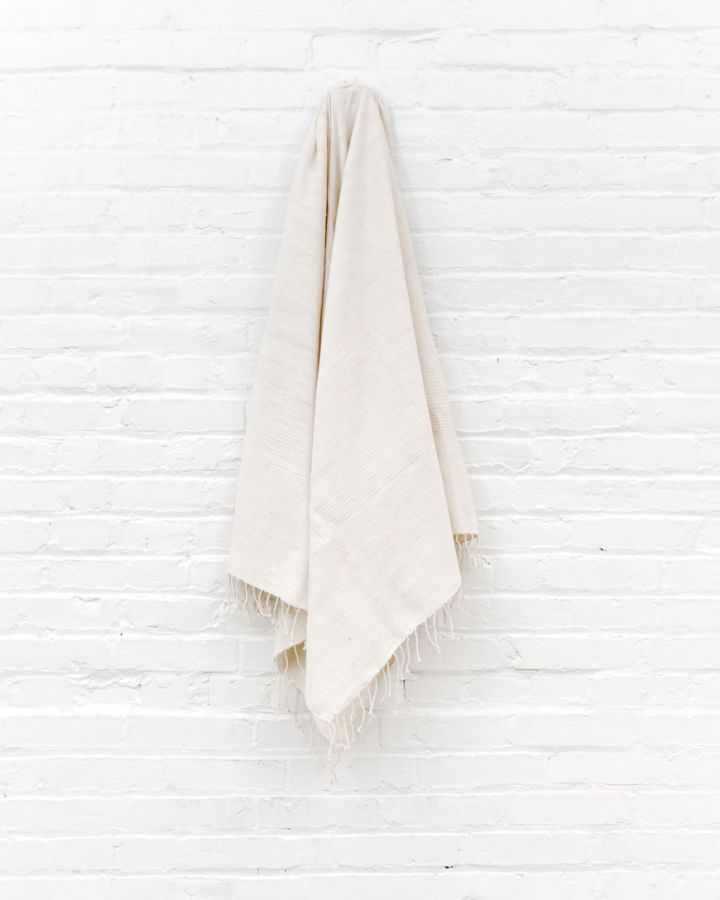 Beige towel hanging on a white textured wall