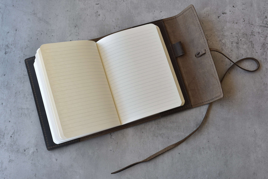 Open notebook with a brown leather cover on a gray surface