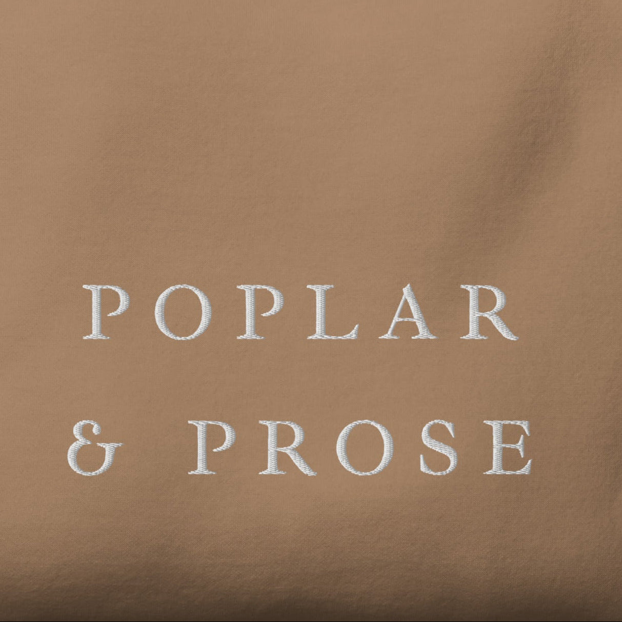 Folded brown shirt with 'Poplar & Prose' embroidered in white