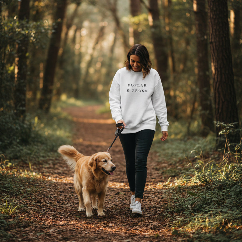 Woman walking her dog on a forest trial wearing the Poplar & Prose sweatshirt in white