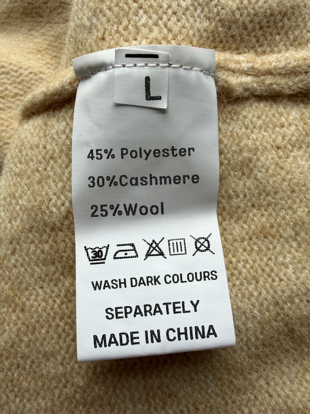 Clothing label on a beige fabric background with text and symbols.