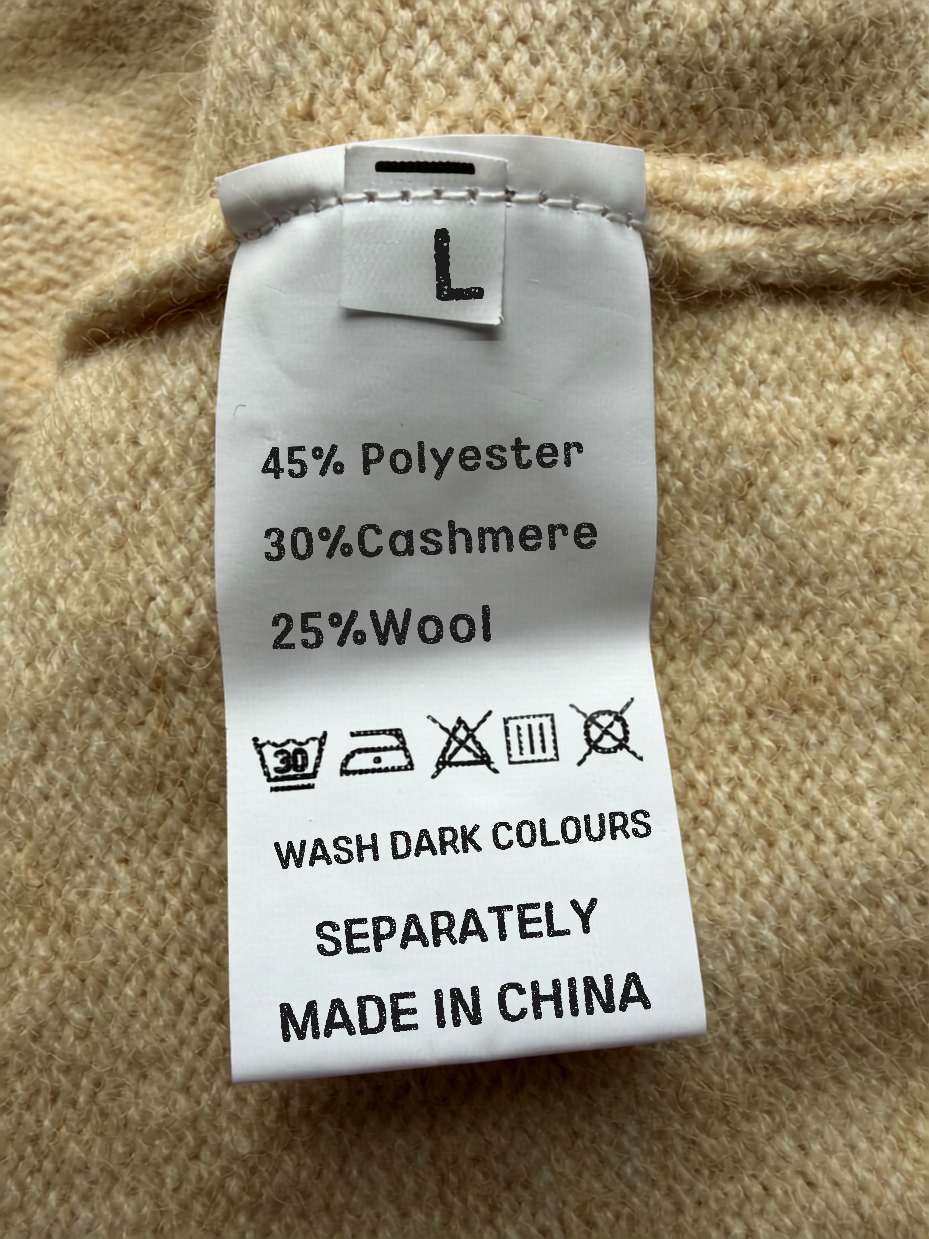 Clothing label on a beige fabric background with text and symbols.