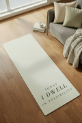 Yoga mat with motivational quote on a wooden floor in a living room setting