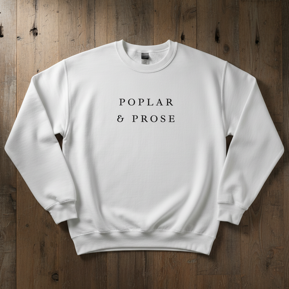 White sweatshirt with 'Poplar & Prose' text on a wooden background
