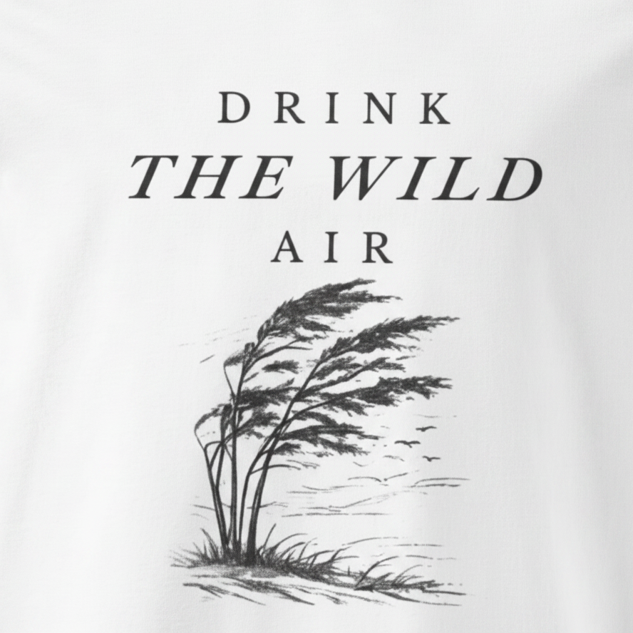Black and white illustration of tall grass with 'Drink the Wild Air' text on a light background, close up of tee