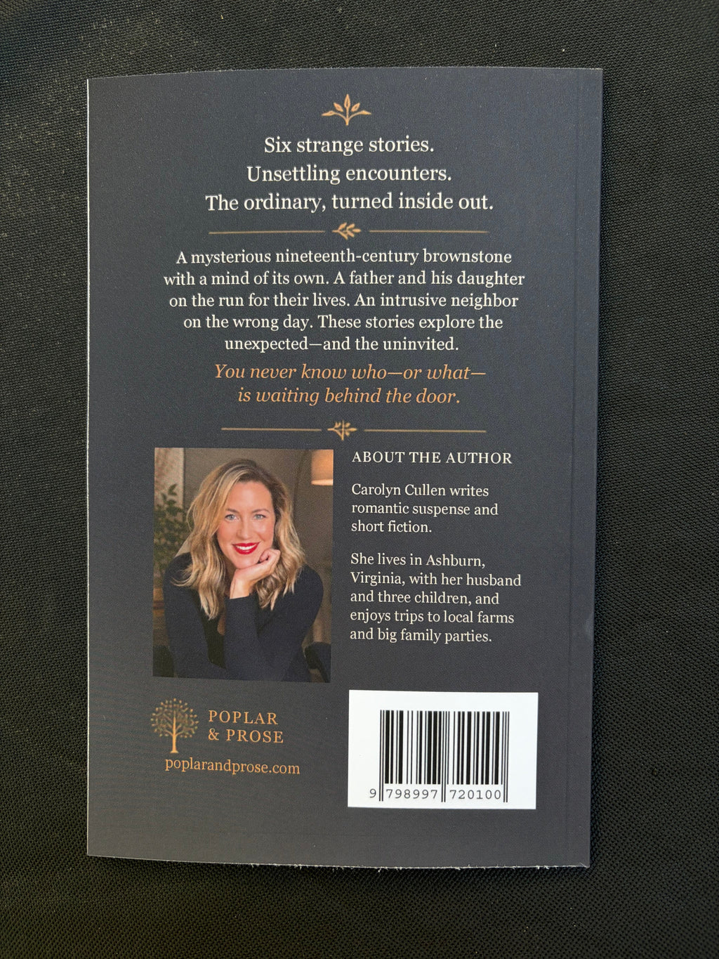 The back cover of the book 'Six Strange Stories' by Repliar Books, featuring a dark gray background with white text, a barcode, and a small portrait of the author, photographed on a black textured fabric background.