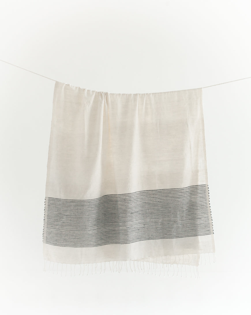 White towel with navy striped pattern hanging on a white background
