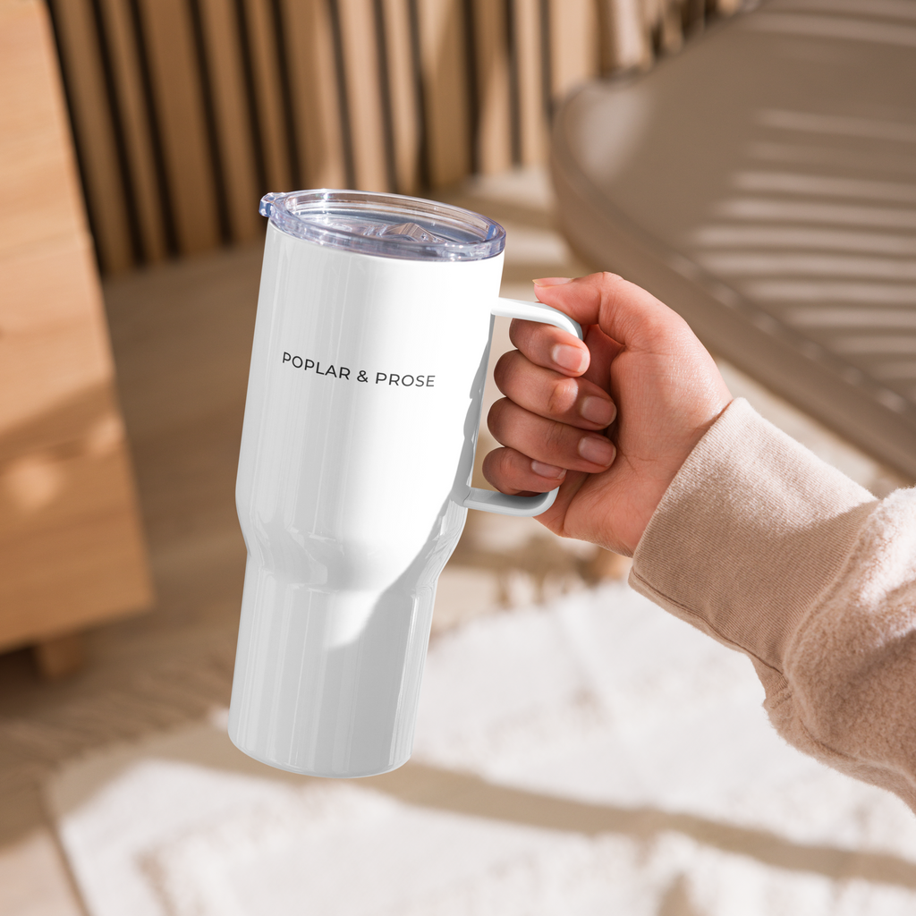 Hand holding a white mug with text in a blurred indoor setting