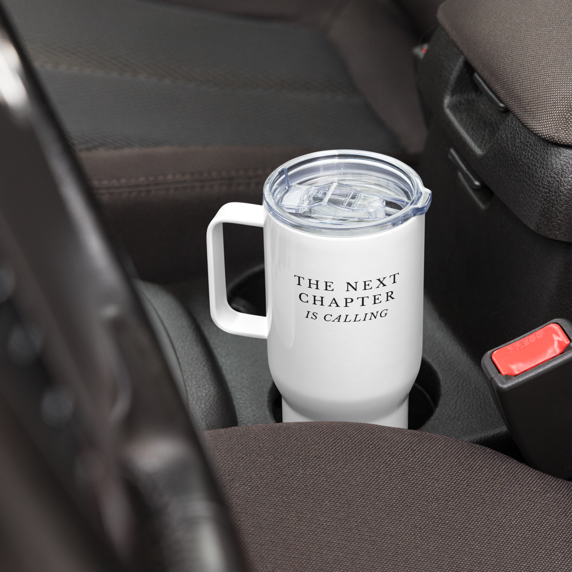 White mug with 'The Next Chapter is Calling' text in a car cup holder.