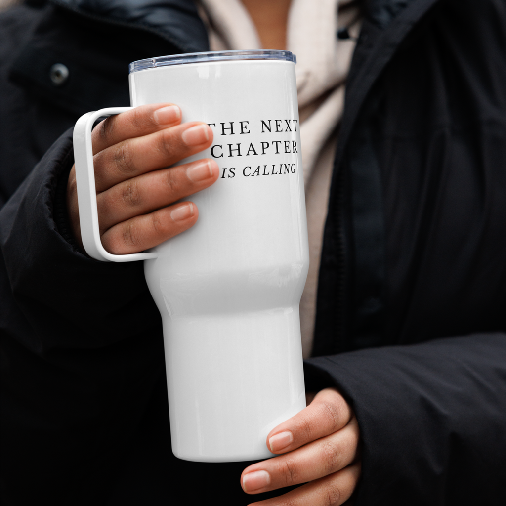 Person holding a white tumbler with a heart and heartbeat design, wearing a black jacket.