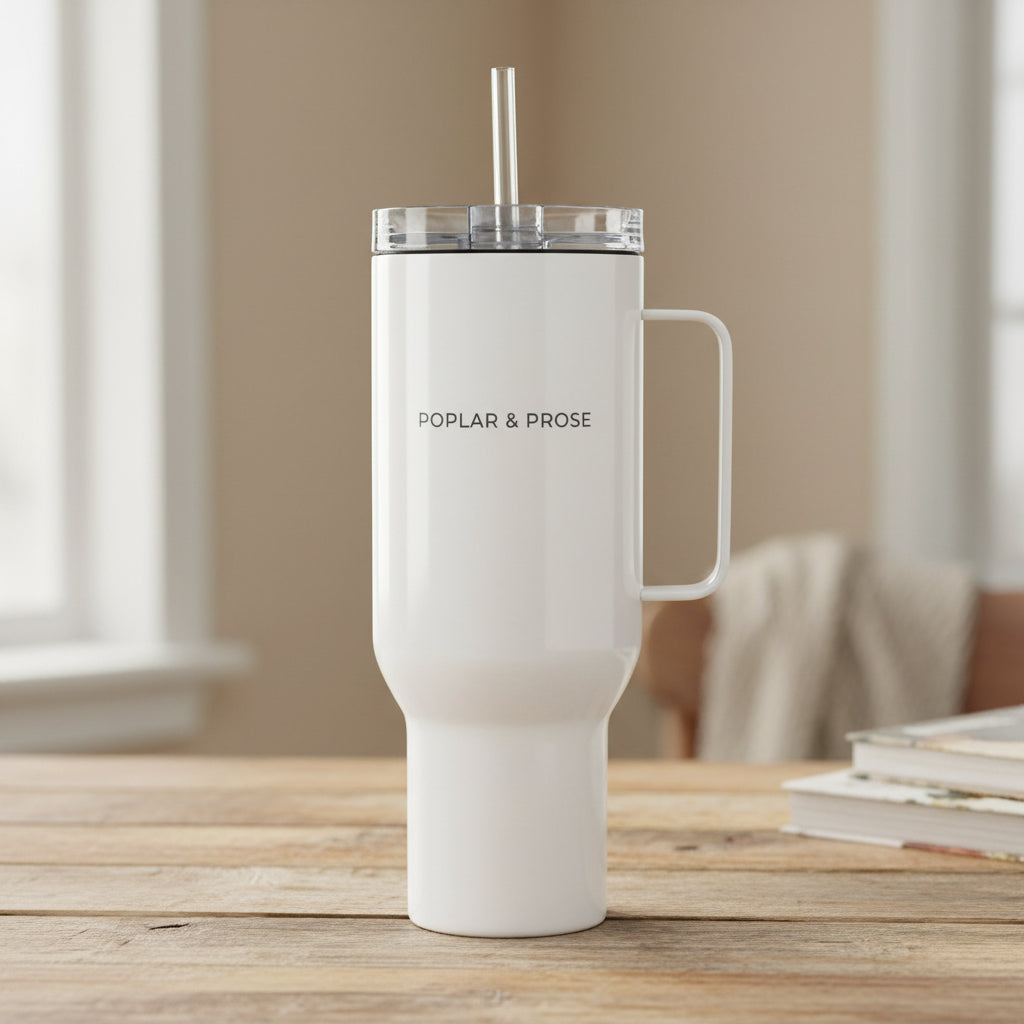 White insulated tumbler with handle and straw on a reclaimed wood table Poplar & Prose side 40 oz