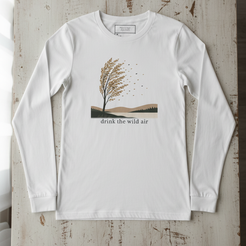 long sleeve white tee with windswept tree, hills, and 'drink the wild air' on a reclaimed wood surface